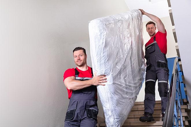 two workers lifting a box spring out of a bedroom in Cottage Grove